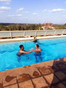 two men are shaking hands in a swimming pool at Coral Bells in Kiambu