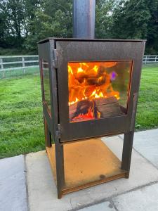 a wood stove with a fire inside of it at Wimbish Hall Cabins in Wimbish
