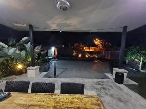 D'Camp Homestay with swimming pool في Kampong Kenangan: فناء مع طاولة وكراسي في الليل