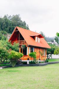 ein Holzhaus mit einem orangenen Dach auf einem Feld in der Unterkunft Hostería Molino de Café 