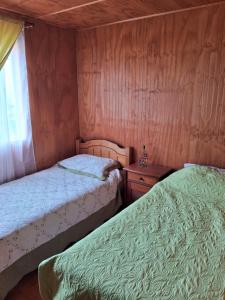 2 camas en una habitación pequeña con ventana en Casa Independiente Ciudad de Chonchi en Chonchi