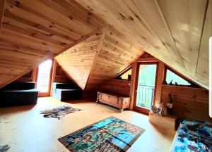 an attic room with a wooden ceiling and windows at Alpakowy raj in Nowy Targ