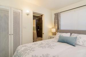a bedroom with a white bed with a blue pillow at Mission Bay Cottage - Bay View Patio, Parking, WasherDryer in San Diego