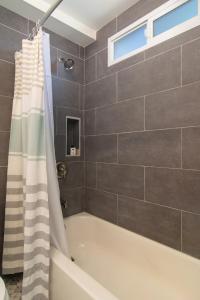 La salle de bains est pourvue d'une baignoire avec rideau de douche. dans l'établissement Mission Bay Cottage - Bay View Patio, Parking, WasherDryer, à San Diego