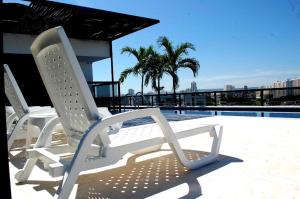 duas cadeiras brancas sentadas ao lado de uma piscina em Hotel Cartagena DC em Cartagena de Indias