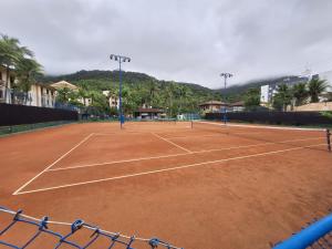 a tennis court with two tennis rackets on it at PARAÍSO Ubatuba - Praia Grande-Toninhas - Apartamento Cond Wembley Tenis in Ubatuba