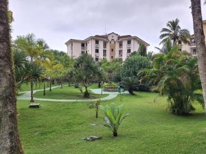 a park with palm trees and a large building at PARAÍSO Ubatuba - Praia Grande-Toninhas - Apartamento Cond Wembley Tenis in Ubatuba
