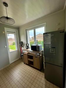 a kitchen with a refrigerator and a counter with a microwave at Gîte "clé de la Baie" avec jacuzzi jusqu'à 7 pers in Woincourt