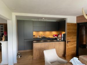 een keuken met zwarte kasten en een witte stoel bij Apartment Palueda in Davos-Dorf in Davos