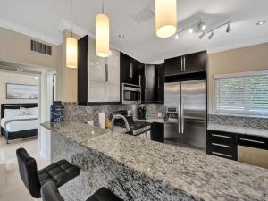 a kitchen with a granite counter top and a bedroom at Beach Isles Modern 1BR in Fort Lauderdale with Patio in Fort Lauderdale