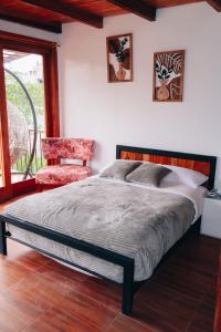 ein Schlafzimmer mit einem Bett und einem roten Stuhl in der Unterkunft Hostería Molino de Café 