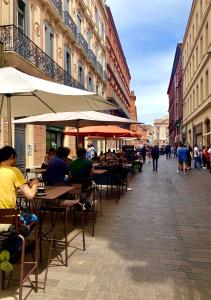 a group of people sitting at tables on a street at Le Romi - Capitole Hypercentre - Appart Cosy in Toulouse