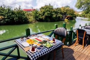 a table with food on a deck next to a river at Taş Mahall Luxury Hotel in Sile
