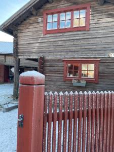 ein Holzhaus mit einem roten Zaun davor in der Unterkunft Stallet - Hemma hos Mait in Mora