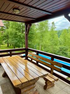 un banco de madera sentado en un porche con vistas a los árboles en Ecotourism Mrežnica, en Mrežnica