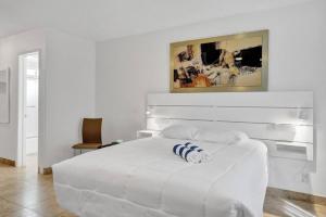 ポンパノビーチにあるWaves Beach Town Studio Apartmentの白いベッドルーム(白と青の枕が付いた白いベッド付)