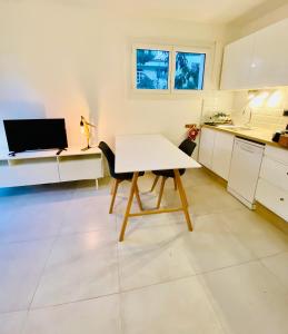 eine weiße Küche mit einem weißen Tisch und einem TV in der Unterkunft Les pieds dans le sable in Argelès-sur-Mer