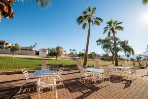 a patio with tables and chairs and palm trees at Golf Course Luxury Retreat on Hogan in Lake Havasu City