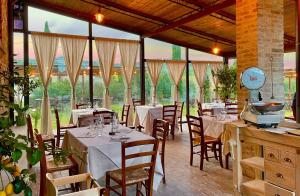 un restaurante con mesas y sillas blancas y ventanas en Locanda Le Giunche, en Guardistallo