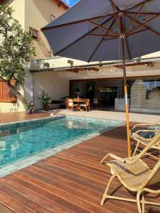 einen Pool mit einem Sonnenschirm, Stühlen und einem Tisch in der Unterkunft Casa Jacarandá in Alto Paraíso de Goiás