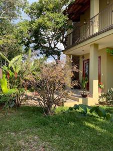 ein Haus mit einem Garten mit einem Baum davor in der Unterkunft Casa Jacarandá in Alto Paraíso de Goiás
