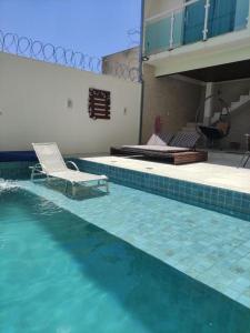 a swimming pool with two chairs and a bed at Espaço Lux Betim in Betim