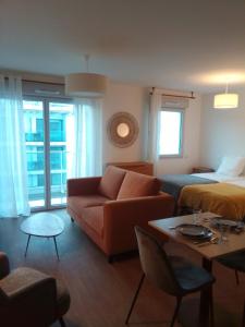 ein Wohnzimmer mit einem Sofa und einem Bett in der Unterkunft Zenao Appart'hôtels Boulogne-sur-Mer - La Rose des Vents in Boulogne-sur-Mer