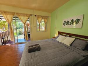 a bedroom with a large bed with green walls at Baan suan khun ta บ้านพักสวนคุณตา in Ko Chang