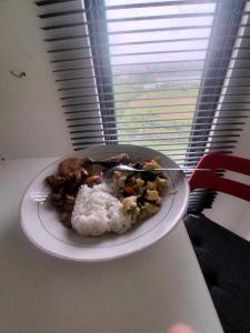un plato de comida con arroz en una mesa en Studio Healing at Sayana Apartemen Harapan Indah Bekasi, 