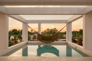 a hammock in a room with a swimming pool at Hotel Sureño Yucatan in Mérida