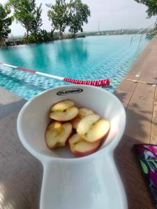 Un jarrón blanco con comida al lado de una piscina en Studio Healing at Sayana Apartemen Harapan Indah Bekasi, 