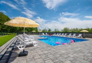 a pool with white lounge chairs and an umbrella at Domki Świt in Wicie