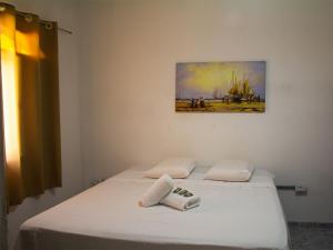 a bedroom with two white beds with a painting on the wall at Pousada Yurgs in Caraguatatuba