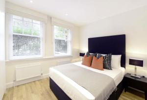 a bedroom with a large bed and two windows at Bond Street Mayfair Penthouse Sleeps up to 6 in London