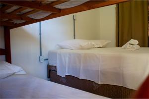 two beds in a room with white sheets and pillows at Pousada Yurgs in Caraguatatuba