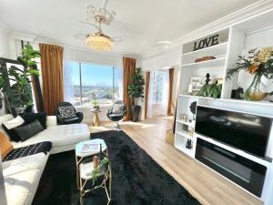 a living room with a white couch and a large tv at Top Floor, Sleeps 4, Queen Mary, Ocean, City Views in Long Beach