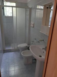 a white bathroom with two toilets and a sink at Perla Marina in San Nicola