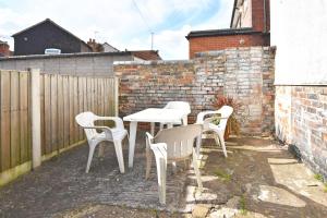 a group of white tables and chairs on a patio at London House by YourStays - 5 Bedroom House in Newcastle-under-Lyme in Stoke on Trent