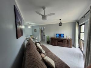 sala de estar con sofá y TV en Maravilhoso apto à beira-mar en Caraguatatuba
