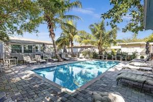 a swimming pool with lounge chairs and palm trees at The Oceans Cozy 2BR Apartment in Victoria Park in Fort Lauderdale