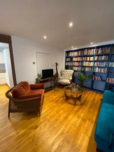 a living room filled with furniture and bookshelves at Modern 1BD Farmhouse-Style Flat - Dalston! in London
