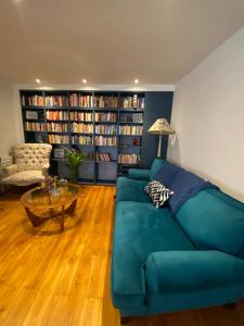Modern 1BD Farmhouse-Style Flat - Dalston! في لندن: غرفة معيشة مع أريكة زرقاء وأرفف كتب