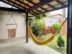 a hammock hanging from a pergola in a backyard at Aconchegante casa perto da praia in Fundão