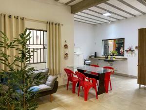 a living room with a table and red chairs at Aconchegante casa perto da praia in Fundão