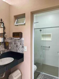 a bathroom with a shower and a sink and a toilet at Aconchegante casa perto da praia in Fundão