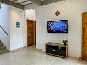 a living room with a tv on a wall at Aconchegante casa perto da praia in Fundão