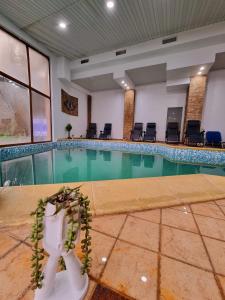 una piscina in un grande edificio con sedie di Hotel Perla Oltului a Caciulata
