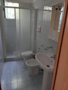 a white bathroom with two toilets and a sink at Perla Marina in Peschici