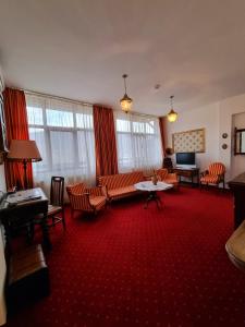 un soggiorno con sedie arancioni e un tappeto rosso di Hotel Perla Oltului a Caciulata