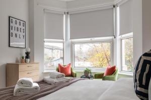 1 dormitorio con 1 cama, 2 sillas y ventanas en Beautiful 3BR Flat with Desks and Fast Wi-Fi en Londres